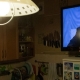Photo d'un homme assis dans son salon, dans l'obscurité, en train de regarder Vladimir Poutine à la télévision